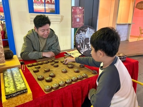 柯秋楓與市民下椰雕象棋。人民網(wǎng) 陳葉欣攝