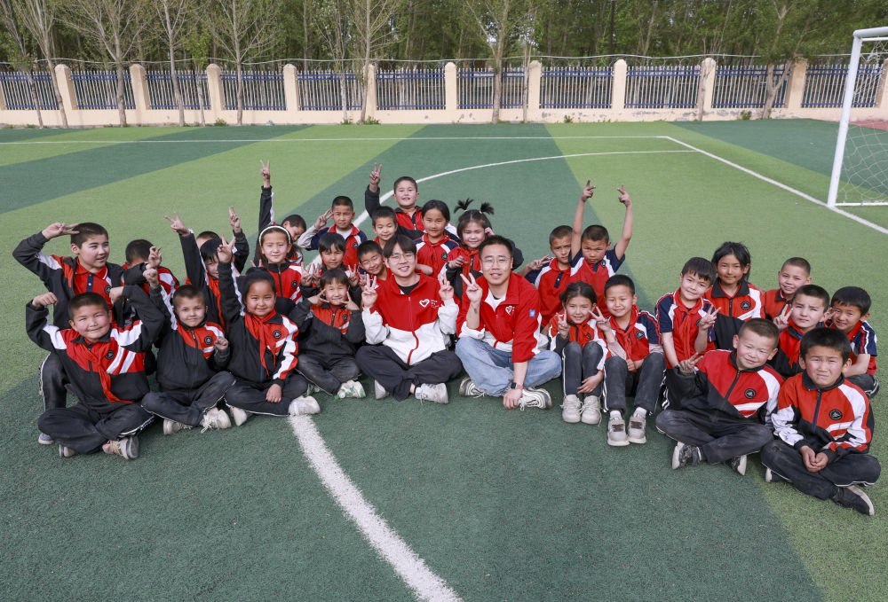 4月23日，在新疆克州阿圖什市哈拉峻鄉(xiāng)謝依特小學，支教教師王俊文（中左）、李軻凡（中右）和學生在一起。