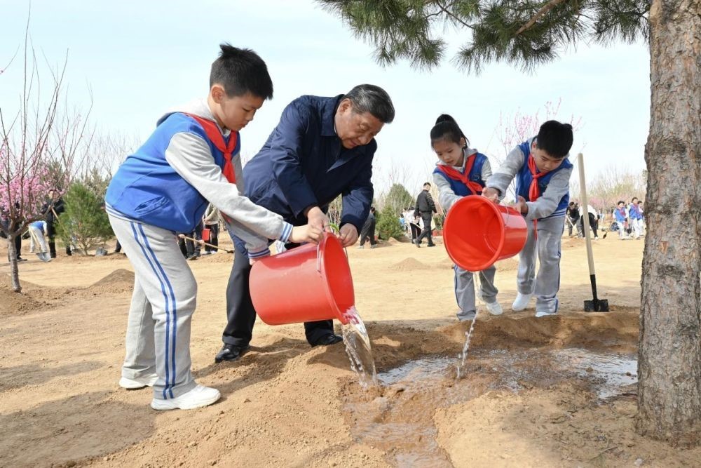 2025年4月3日，習近平總書記等來到北京市豐臺區(qū)永定河畔參加首都義務植樹活動。這是習近平總書記同少先隊員一起給剛栽下的樹苗澆水。新華社記者 謝環(huán)馳 攝
